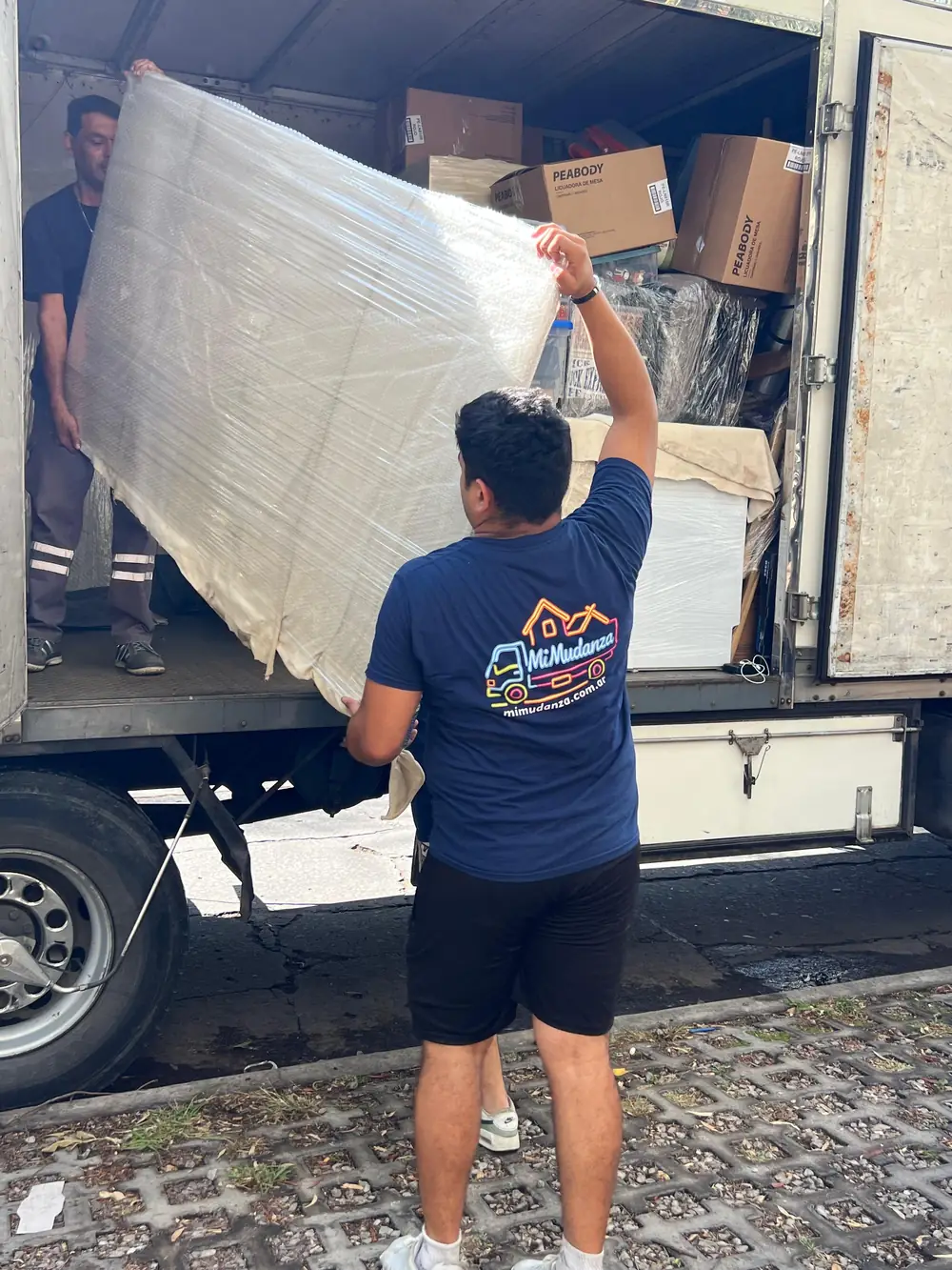 Operario cargando muebles embalados al camión de mudanza